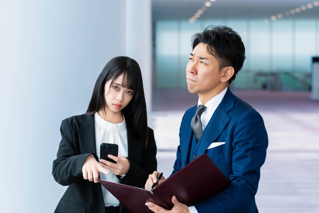 書類を見ながら悩んでいる社会人の男女